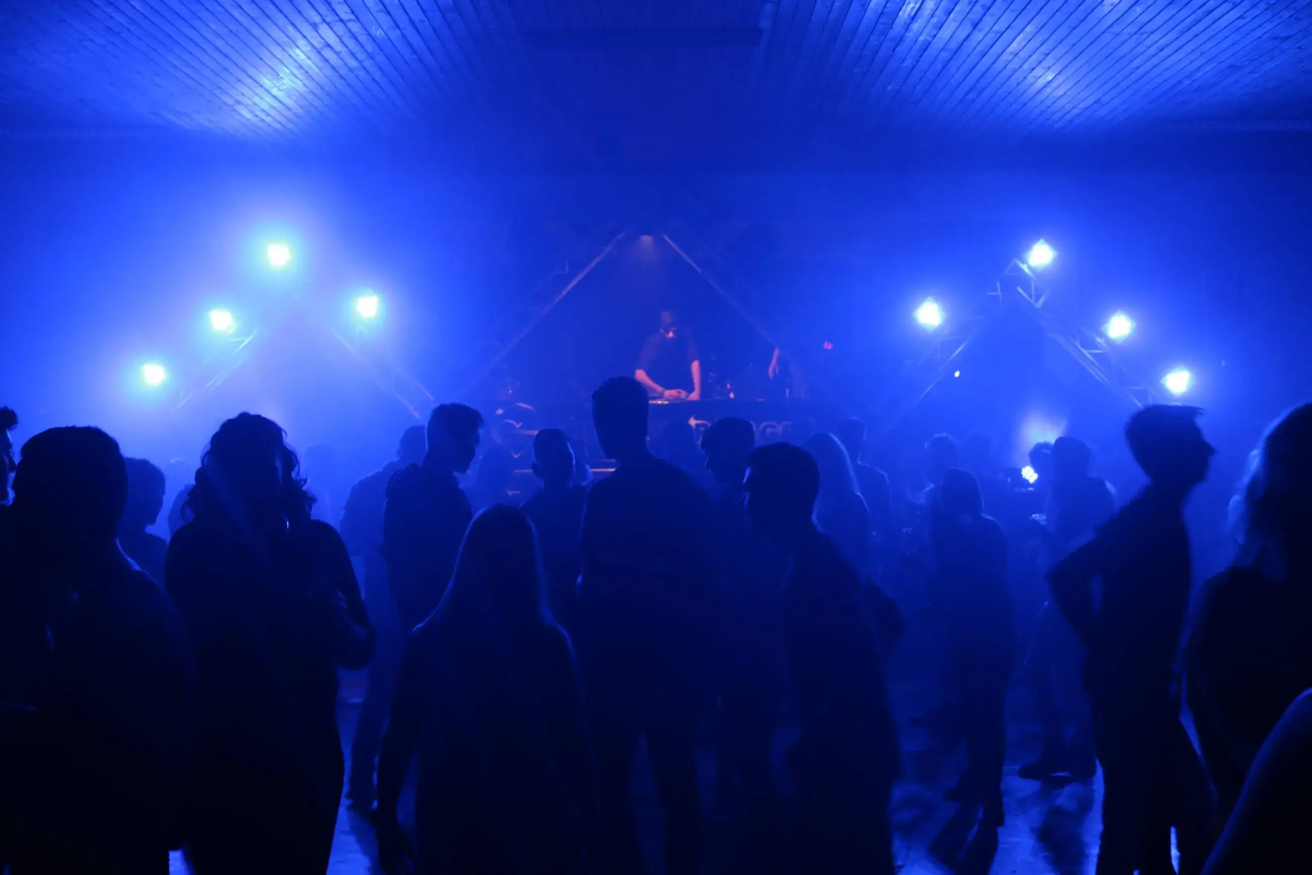 Publikum vor einer Bühne mit blauer Beleuchtung in einer Halle